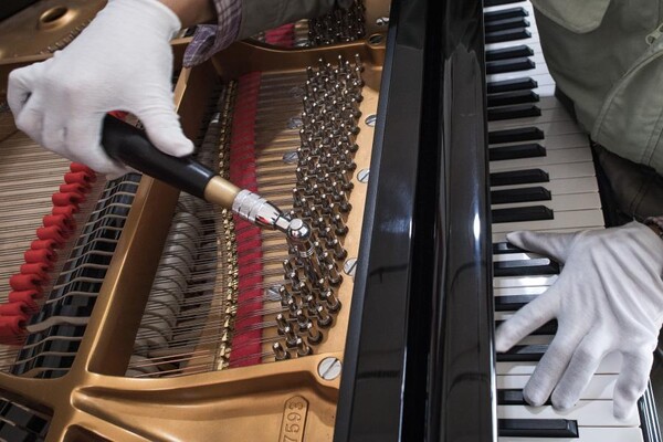 지난 23일 촬영한 파슨스음악그룹의 이창 피아노 생산공장. 흰 장갑을 낀 공장 직원이 피아노 현을 고정하는 핀이 풀리지 않도록 도구를 이용해 조이고 있다.