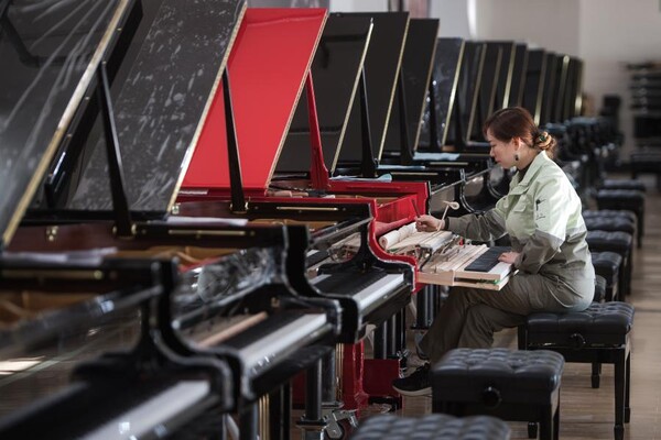 작업복을 입은 공장 직원이 지난 23일 피아노를 조율하고 있다.
